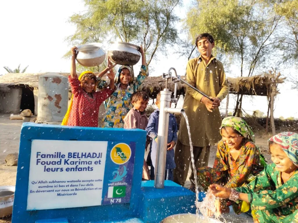 Happy children around a well in a rural village.