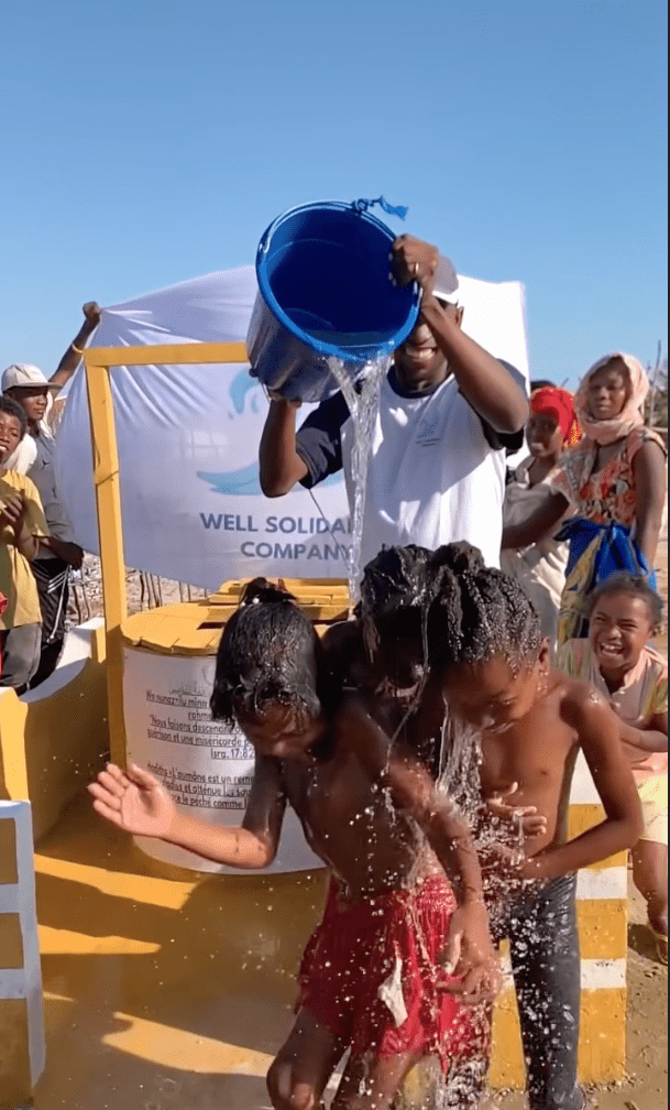 Children playing under water poured from a bucket.