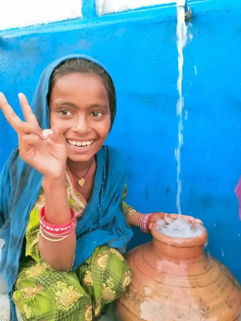 Young girl smiling in front of a clay pot.