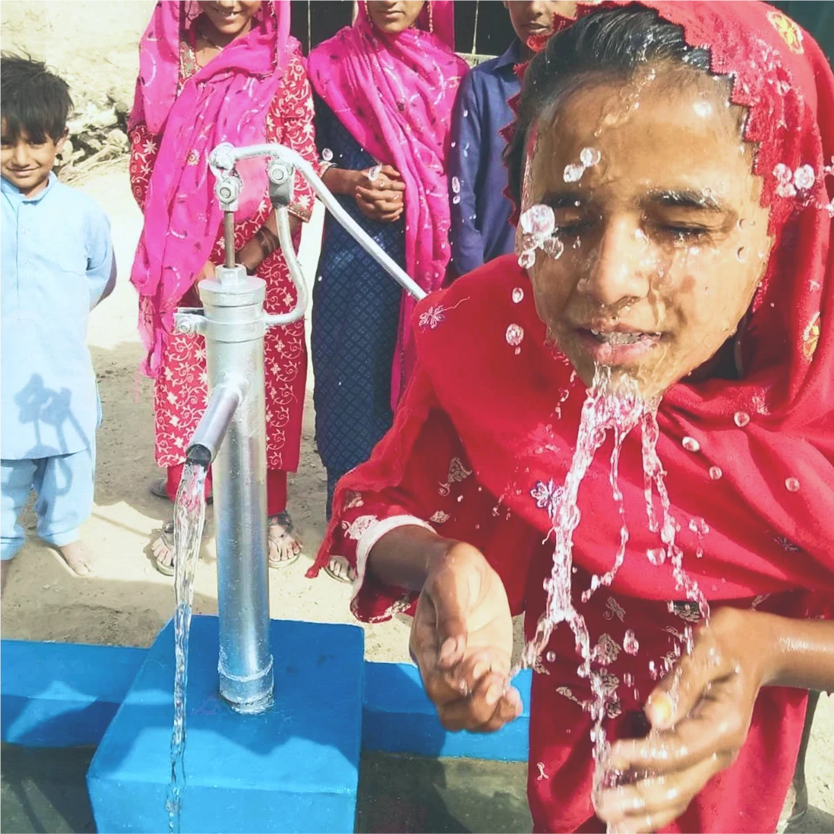 Woman drawing water from a hand pump.