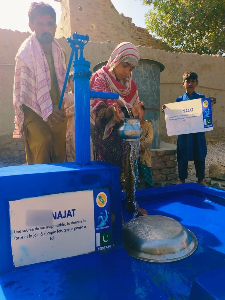 Girl filling a blue pot at a hand-pump well in Pakistan, plaque with a personal message to Najat